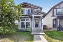 Two-story residence featuring a covered front porch, concrete pathway, and mature landscaping - 9847 220 Street, Edmonton, AB 
