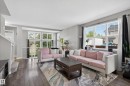 Spacious living area featuring expansive windows, wood-finish flooring, and light gray wall tones - 9847 220 Street, Edmonton, AB 
