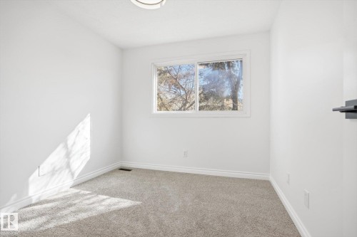 Room featuring neutral gray carpet flooring, white baseboards, and a white ceiling with a flush-mount light fixture - 857 Erin Place, Edmonton, AB 