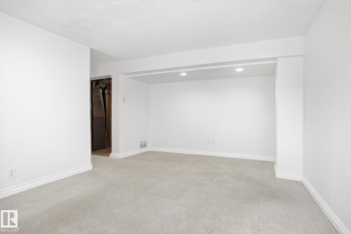 Expansive room featuring light gray carpeting, white painted walls, and white baseboards - 857 Erin Place, Edmonton, AB 