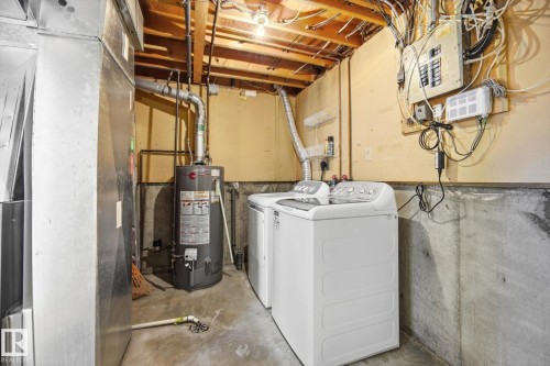 Utility area featuring concrete flooring, exposed ceiling joists, and a water heater - 857 Erin Place, Edmonton, AB 