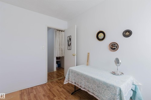 Room featuring wood-finish flooring, white painted walls, and a doorway leading to a separate area - 4 14310 80 Street, Edmonton, AB 
