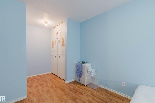 Interior space featuring wood-finish flooring, light blue wall paint, and white baseboards - 4 14310 80 Street, Edmonton, AB 