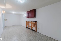 Spacious interior room featuring light-toned square tile flooring, a wall-mounted red wood-finish storage cabinet, a small window with light-colored curtains, and two ceiling-mounted dome lights providing illumination - 