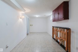 Spacious room featuring light-toned tiled flooring, white painted walls, and a textured ceiling - 