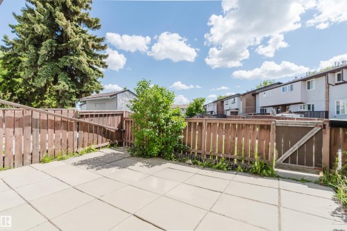 Expansive patio area featuring large square pavers, surrounded by a wood-slat fence - 4 14310 80 Street, Edmonton, AB 