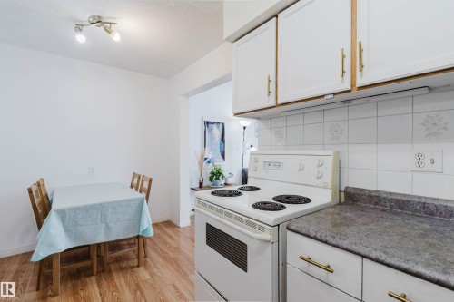 Kitchen featuring white cabinetry with gold-tone hardware, a white electric range, and a gray countertop - 4 14310 80 Street, Edmonton, AB 