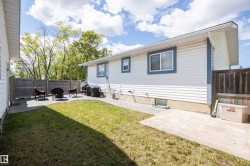 Fenced backyard featuring a paved patio area, green lawn, and gravel pathway - 