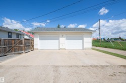 Detached two-car garage with white vinyl siding and a gray shingled roof - 