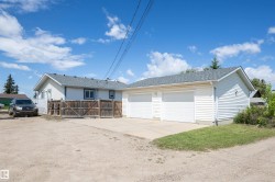Two-car attached garage with concrete driveway, light blue siding, and a wooden fence - 