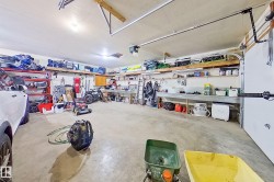 Spacious garage featuring concrete flooring, built-in shelving, expansive workbench, dual overhead garage door tracks, and ceiling-mounted lighting - 