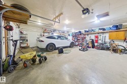 Spacious garage with a concrete floor, overhead storage shelving, mounted wall shelving, recessed lighting, and a white garage door - 