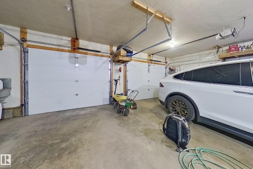 Attached two-car garage featuring a concrete floor, two white paneled garage doors, and exposed wooden framing - 10232 101 Street, Westlock, AB 
