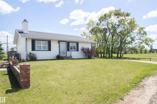 White vinyl-sided residence with dark shutters and a light-colored roof - 10232 101 Street, Westlock, AB 