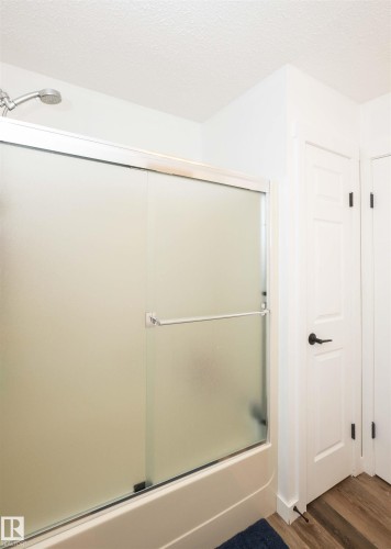Bathtub with sliding frosted glass enclosure and chrome fixtures - 10232 101 Street, Westlock, AB 