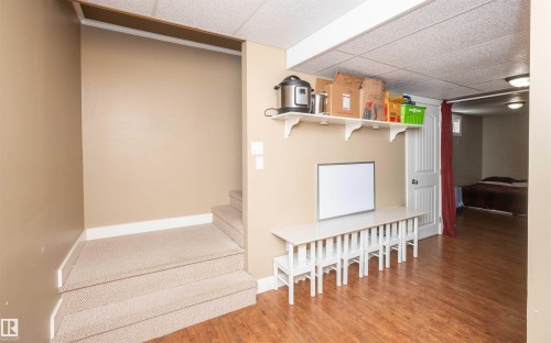 Carpeted stairs leading to an upper level, with wood-finish flooring in the lower area - 10232 101 Street, Westlock, AB 