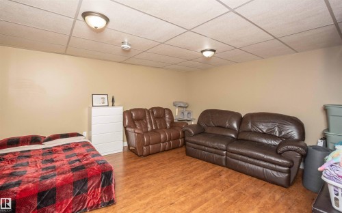 Neutral wall paint, wood-finish flooring, and a grid ceiling with flush-mount lighting fixtures - 10232 101 Street, Westlock, AB 