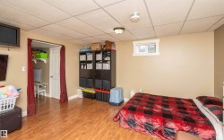 Spacious lower-level room featuring wood-finish flooring, a neutral wall color, and a drop ceiling - 