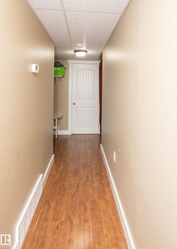 Hallway featuring wood-finish flooring, light beige walls, and white baseboards - 10232 101 Street, Westlock, AB 