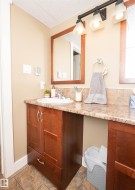 Bathroom vanity featuring a built-in sink, wood-finish cabinetry, a framed mirror, and a three-light fixture - 