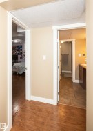 Hallway featuring wood-finish flooring, neutral wall paint, and white trim - 