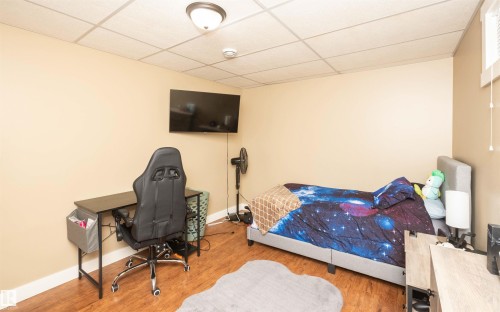 Room featuring wood-finish flooring, recessed lighting, a mounted television, and neutral-toned walls - 10232 101 Street, Westlock, AB 