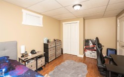 Room featuring wood-finish flooring, a window with white trim, and bi-fold closet doors - 
