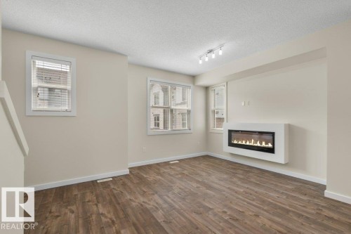 Spacious room featuring wood-finish flooring, white baseboards, and neutral wall tones - 125 655 Watt Boulevard, Edmonton, AB 