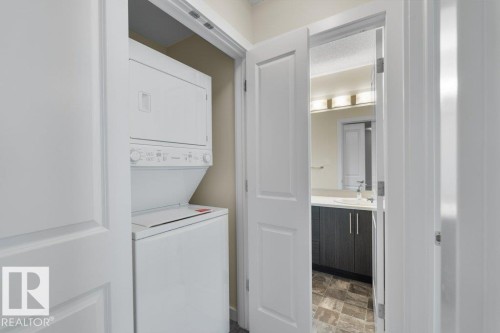 Compact laundry closet with stacked white appliances - 125 655 Watt Boulevard, Edmonton, AB 