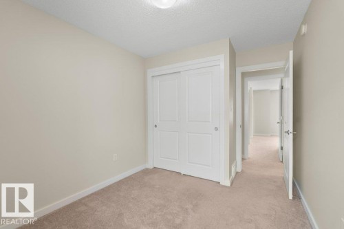 Neutral-toned room featuring a ceiling-mounted light fixture, light beige walls, and light brown carpeting - 125 655 Watt Boulevard, Edmonton, AB 