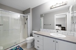Bathroom featuring a single vanity with a laminate countertop, white subway tile backsplash, and a large wall-mounted mirror - 