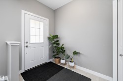 Entryway featuring a white door with divided light window, brushed nickel hardware, and light-toned tile flooring - 