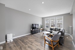 Spacious living area featuring wood-finish flooring, recessed lighting, and light gray wall tones - 
