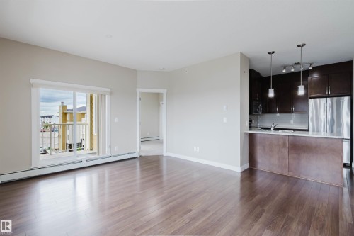Open-concept living area featuring wood-finish flooring and neutral wall tones - 402 3670 139 Avenue, Edmonton, AB 