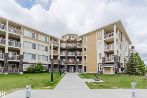 Multi-story building exterior featuring a neutral color palette, stone accents, and multiple private balconies with white railings - 402 3670 139 Avenue, Edmonton, AB 