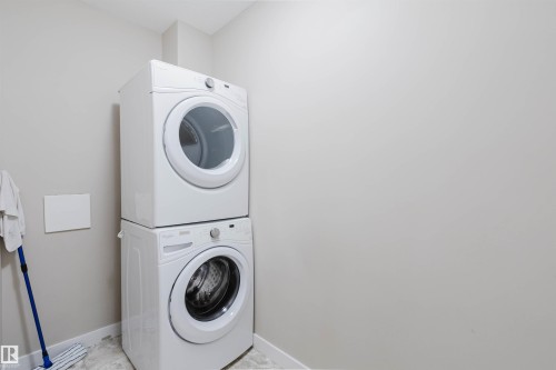 Dedicated laundry area featuring a white stackable washer and dryer set - 402 3670 139 Avenue, Edmonton, AB 