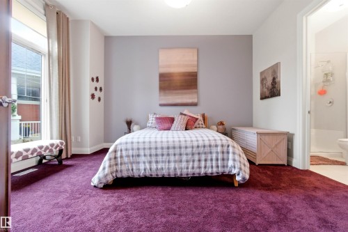 Plush purple carpeting grounds this room featuring a window with exterior balcony access - 9003 16 Avenue, Edmonton, AB 