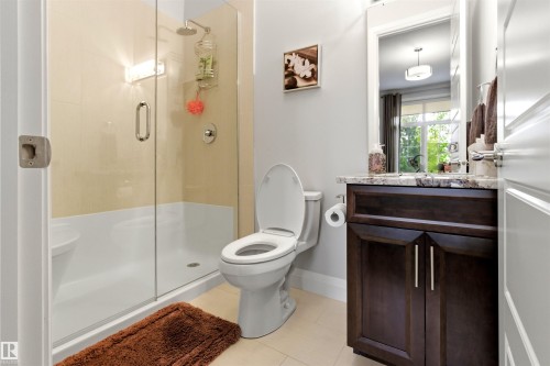 Bathroom featuring a walk-in shower with clear glass enclosure and light-toned tile surround - 9003 16 Avenue, Edmonton, AB 