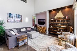 Spacious living area featuring high ceilings, dark wood-finish flooring, and a built-in recessed shelving unit with accent lighting - 