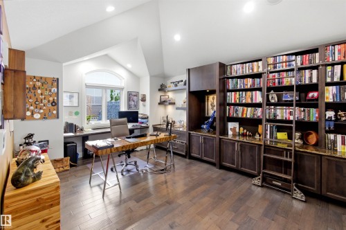 Dedicated room featuring extensive built-in shelving, wood-finish flooring, recessed lighting, and a window with an arched transom - 9003 16 Avenue, Edmonton, AB 