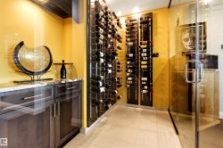 Custom wine storage area featuring glass enclosure, built-in shelving for bottle display, and wood-finish flooring - 