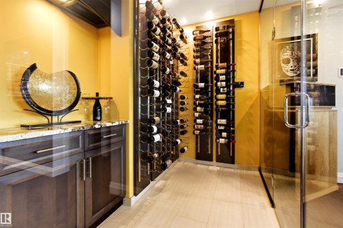 Custom wine storage area featuring glass enclosure, built-in shelving for bottle display, and wood-finish flooring - 9003 16 Avenue, Edmonton, AB 