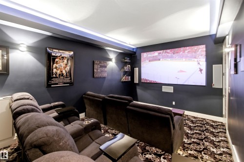 Dedicated media room featuring a large projection screen, recessed ceiling lighting, and wall-mounted sconces - 9003 16 Avenue, Edmonton, AB 