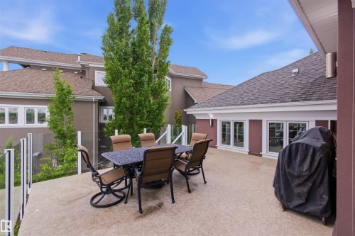 Expansive exterior deck featuring a concrete surface, glass panel railing, and multiple window accents - 9003 16 Avenue, Edmonton, AB 