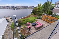 Waterfront property featuring a private dock, stone-clad lower exterior, and a paver patio - 
