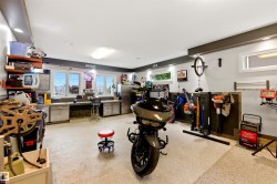 Spacious garage featuring an epoxy-coated concrete floor, abundant overhead lighting, and built-in workbench cabinetry - 