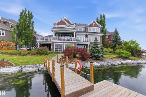 Waterfront property featuring a private wooden dock, manicured landscaping, and a multi-level deck with glass railings - 9003 16 Avenue, Edmonton, AB 
