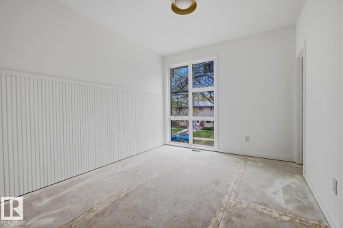 Room featuring a large multi-pane window, white shiplap wainscoting, a flush-mount ceiling light fixture, and neutral white walls - 11327 122 Street, Edmonton, AB - Indoor Photo Showing Other Room