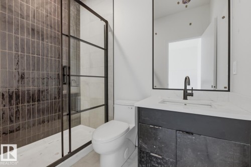 Bathroom featuring a walk-in shower with dark-toned vertical tile and a black-framed glass enclosure - 11327 122 Street, Edmonton, AB - Indoor Photo Showing Bathroom