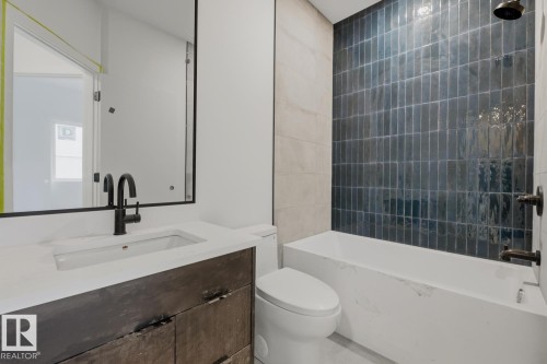 Bathroom featuring a modern vanity with a white countertop and dark wood-finish cabinetry, a recessed sink with a matte black faucet, and a large wall mirror - 11327 122 Street, Edmonton, AB - Indoor Photo Showing Bathroom